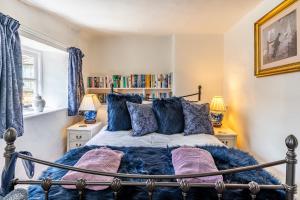 a bedroom with a bed with blue pillows at Forsythia Cottage in Bourton on the Water