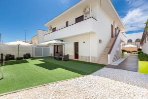 una casa blanca con césped verde en Joy Home Apartments by BarbarHouse, en Maruggio