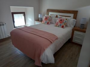 um quarto com uma cama grande com lençóis e almofadas cor-de-rosa em La Lagareta de Olivia em Trevejo