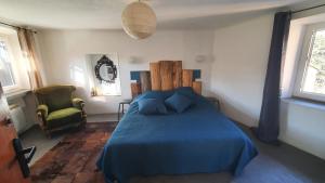 - une chambre avec un lit bleu et une chaise dans l'établissement Duplex avec spa et terrasse en plein centre du village, à Saint-Jean-du-Gard
