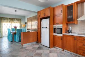 eine Küche mit Holzschränken und einem weißen Kühlschrank in der Unterkunft Zenia Villa in Paradeísion
