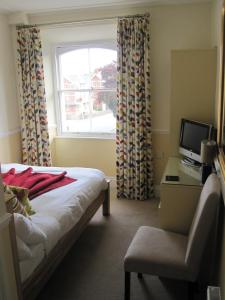 a bedroom with a bed and a chair and a window at Yeo Dale Hotel in Barnstaple