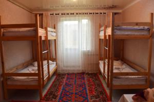 Habitación con 4 literas y alfombra. en Naryn Guest House en Naryn
