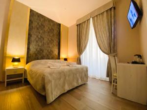 Un dormitorio con una cama y un televisor en una pared. en Hotelier 51, en Roma