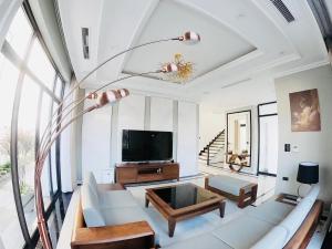 ein Wohnzimmer mit einem weißen Sofa und einem TV in der Unterkunft FLC Villa Hạ Long 5 Phòng Ngủ in Hạ Long