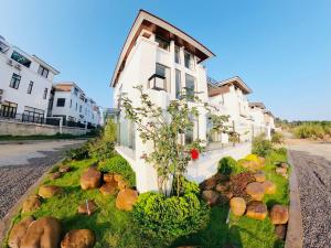 a white house with a tree in front of it at FLC Villa Hạ Long 5 Phòng Ngủ in Ha Long