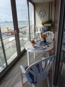 Biały stół i krzesła w pokoju z balkonem w obiekcie Apt de charme, les pieds dans l'eau w mieście Plérin