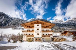 a building in the snow with mountains in the background at Alfaierhof-Bergheimat in Gschnitz