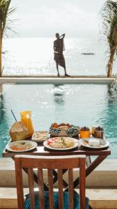 a table with plates of food next to a swimming pool at Villa Hibiscus Zanzibar in Jambiani