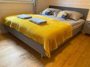 Una cama con manta amarilla y almohadas. en Domki Mechelinki, en Mechelinki