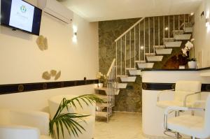 um salão com uma sala de espera com cadeiras brancas e escadas em Il Casanova em Tropea