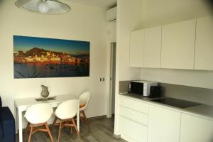 uma cozinha com armários brancos e uma mesa e cadeiras em Le rose di Bino em Sestri Levante