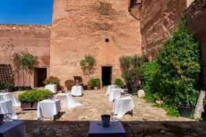 a courtyard with white tables and chairs in front of a building at Castillo De Pilas Bonas in Manzanares