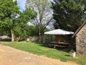 un tavolo da picnic con ombrellone accanto a una recinzione di grange typique du quercy a La Bécade