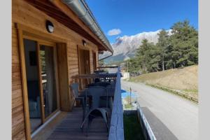 eine Holzterrasse mit Tischen und Stühlen auf einem Haus in der Unterkunft Appartement de charme dans résidence avec piscine La Joue du Loup in Le Dévoluy