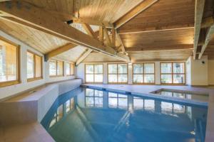 einen großen Innenpool mit Holzdecken und Fenstern in der Unterkunft Appartement de charme dans résidence avec piscine La Joue du Loup in Le Dévoluy