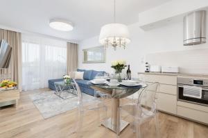 a kitchen and living room with a table and chairs at Baltini Premium Apartament Bliżej Morza in Kołobrzeg