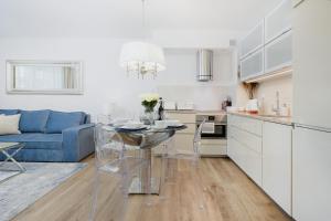 a kitchen and living room with a table and a blue couch at Baltini Premium Apartament Bliżej Morza in Kołobrzeg