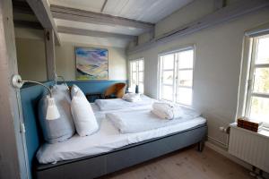 Schlafzimmer mit einem Bett mit weißer Bettwäsche und Kissen in der Unterkunft Gæstgiveri Bregninge in Ærøskøbing