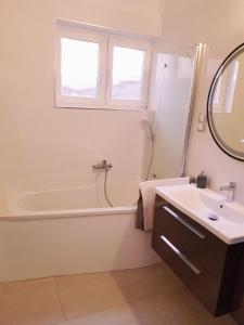 uma casa de banho com uma banheira, um lavatório e um espelho. em Apartment Centar Omis em Omiš