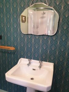 La salle de bains est pourvue d'un lavabo blanc et d'un miroir. dans l'établissement ART DECO 1930s Design, à Napier