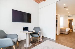 Habitación con mesa, sillas y TV en la pared. en Peninsular en Girona