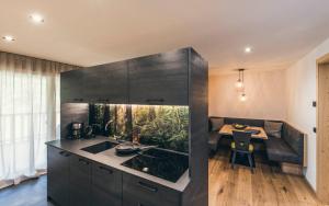 a kitchen with black cabinets and a island with a table at Lichtung Woldererhof Waldluft in Casateia