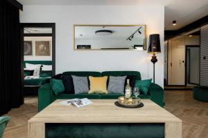 a living room with a green couch and a table at Baltini Premium Apartament Kasprowicza 20 A-B z basenem, saunami i jacuzzi in Kołobrzeg