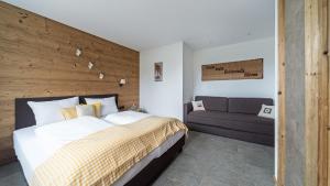 a bedroom with a large bed and a couch at VIERKLEE - Das kinderfreundliche Ferienhaus am Achensee in Maurach