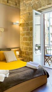 Un dormitorio con una cama amarilla y una pared de ladrillo en B&B Carella en Palermo