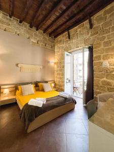 um quarto com uma cama amarela numa parede de pedra em B&B Carella em Palermo