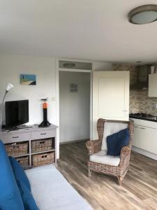 uma sala de estar com um sofá e uma cadeira em Vakantiehuisje in Ouddorp dichtbij het strand em Ouddorp