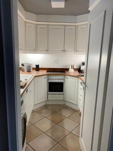 a kitchen with white cabinets and a tile floor at Kliffssand 33 in Kampen