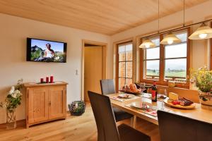 comedor con mesa y TV en la pared en Haus Elfriede en Schwarzenberg im Bregenzerwald