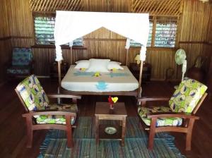 a bedroom with a bed and two chairs and a table at Komba Forever in Nosy Komba