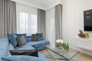 a living room with a blue couch and a glass table at Apartament Baltini Premium Polanki Park in Kołobrzeg