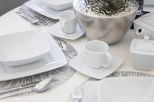 a table with white plates and silverware on it at Apartament Baltini Premium Polanki Park in Kołobrzeg