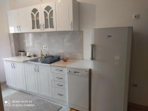cocina con armarios blancos y nevera en Vaikiki Apartman LM, en Novi Pazar