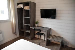 a room with a desk with a tv and a chair at La Marine in Sibiril