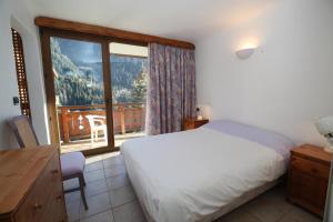 een slaapkamer met een bed en een groot raam bij Chalet Bouquetin- Ecureuil 2 for 10 to 14 people in Champagny-en-Vanoise