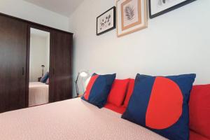 Schlafzimmer mit einem Bett mit roten und blauen Kissen in der Unterkunft APARTAMENTO PLAYA CATEDRALES CON TERRAZA in Barreiros