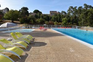 a swimming pool with yellow chairs and an umbrella at Résidence U Nebbiu in Olmeta-di-Tuda