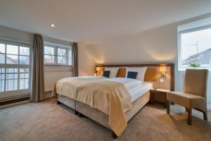 a bedroom with a large bed and a chair at Hotel Am Fischmarkt in Stade