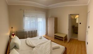 a bedroom with a white bed in a room at Pingvin Cukrászda Apartman felső szint in Balatonmáriafürdő