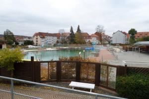 uma piscina com um banco num parque em Apartment Am Kurpark em Bad Frankenhausen