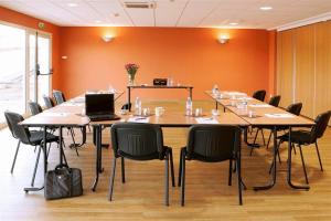 a conference room with a large table with chairs and a laptop at Hôtel Akena City Caudry in Caudry