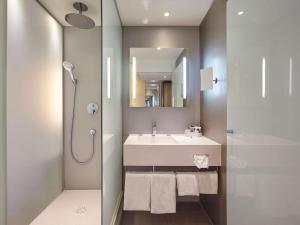 een badkamer met een wastafel, een douche en een spiegel bij Mercure Paris Arc de Triomphe Etoile in Parijs