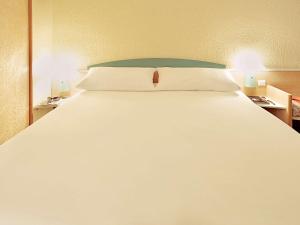 a large white bed in a room with two lamps at ibis Swansea in Swansea