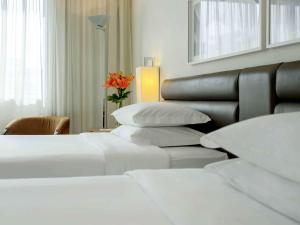 a hotel room with two beds and a vase with a flower at Grand Mercure Sao Paulo Vila Olimpia in Sao Paulo