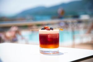 a drink sitting on a table next to a pool at Casa Luis Apartments in Santa Eularia des Riu